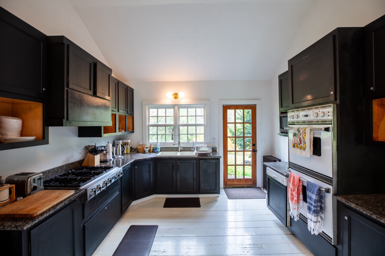 view of kitchen facing sink, stove and ovens.